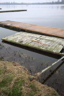 Bulutlu bir günde, üzerinde bir kürekle göl kıyısında yüzen denizaltıları.