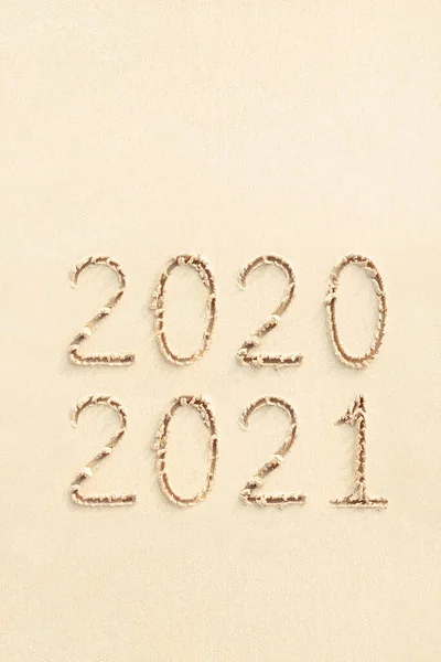 2020 ve 2021 plajda el yazısıyla yazılmış numaralar, sarı kum arka plan.