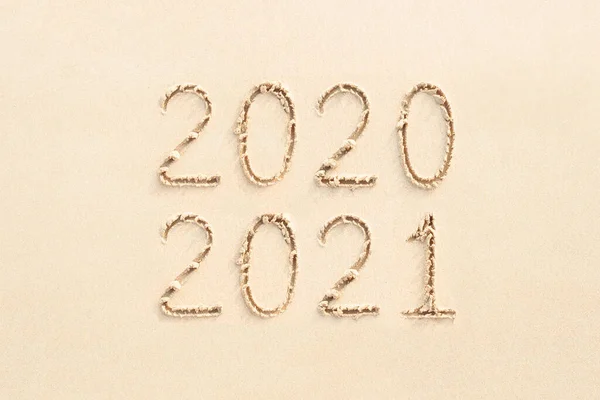 2020 and 2021 handwritten numbers on the beach, yellow sand background — Stock Photo, Image