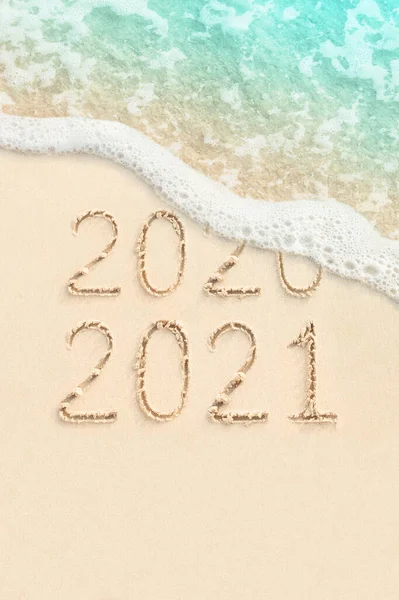 2020 ve 2021 arkaplanda kum, sahil ve okyanus dalgaları üzerine el yazısıyla yazılmış rakamlar