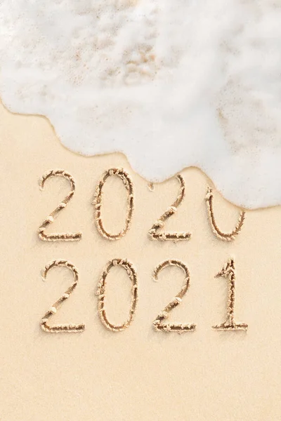 2020 ve 2021 arkaplanda kum, sahil ve okyanus dalgaları üzerine el yazısıyla yazılmış rakamlar