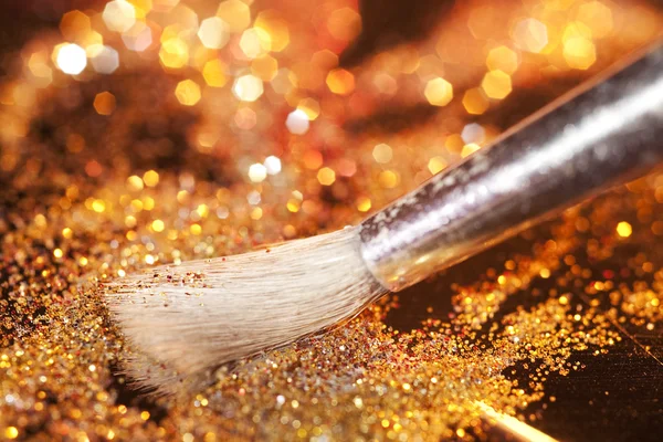 Close-up on makeup brush and gold shining powder — Stock Photo, Image