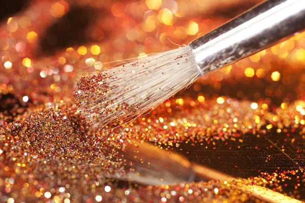 Close-up on makeup brush and gold shining powder — Stock Photo, Image