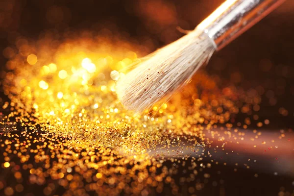 Close-up on makeup brush and gold shining powder — Stock Photo, Image