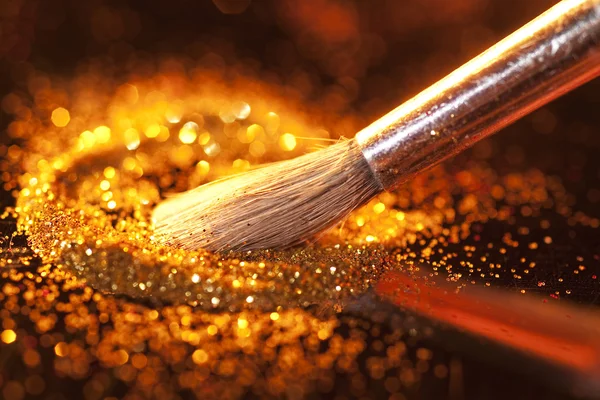 Close-up on makeup brush and gold shining powder — Stock Photo, Image