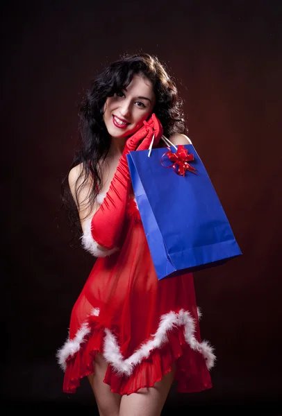 Sexy Santa helper holding a gift. Red dress with feathers — Stock Photo, Image