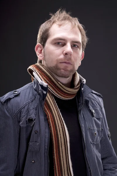 Portret van een jonge man met een jas en sjaal — Stockfoto