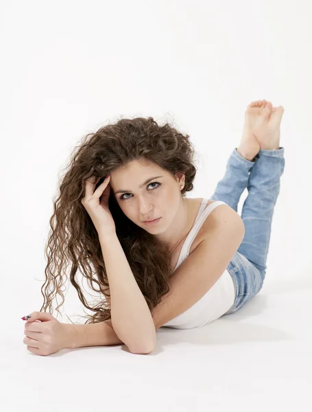 Beautiful girl with long curly hair wearing white top and torn jeans — Stock Photo, Image