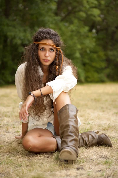 Beautiful hippie girl sitting on a grass in the park — Stock Photo, Image