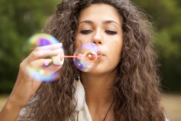 Beautiful hippie girl in the park blowing bubbles — Stock Photo, Image