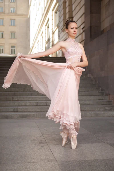 Молодая балерина с красивым розовым платьем позирует на открытом воздухе — стоковое фото
