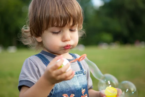 Маленький хлопчик дме мильні бульбашки в парку — стокове фото