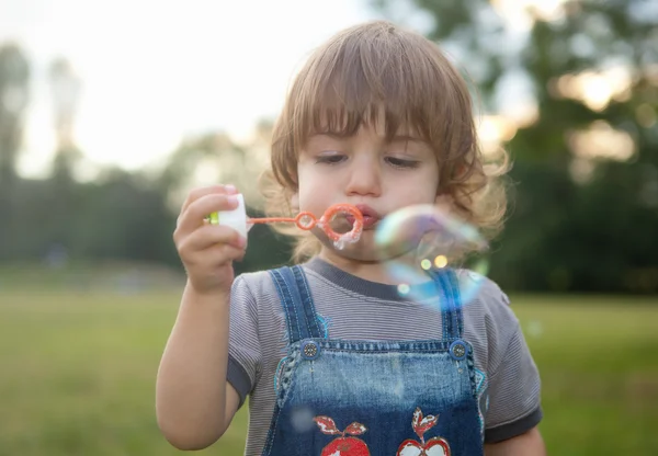 Niño soplando burbujas de jabón en el parque — Foto de Stock