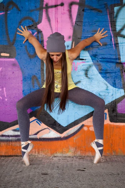 Teenage girl with gray hat dancing in front of graffiti wall — Stock Photo, Image