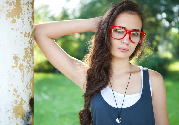 Mladá žena s červenou brýle v parku spočívající — Stock fotografie