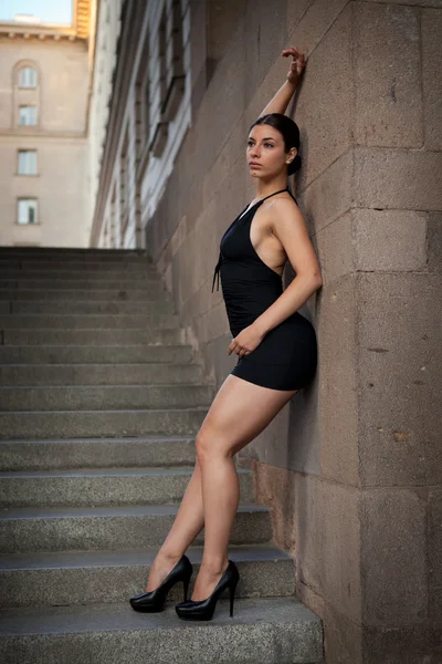 Jonge sexy vrouw met zwarte jurk poseren trap — Stockfoto
