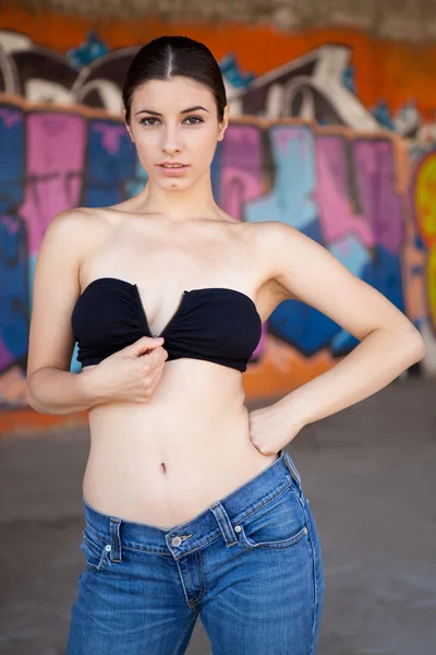 Beautiful girl with black unzip top in front of graffiti wall — Stock Photo, Image