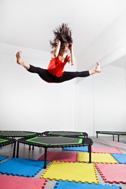 Esmer kadın bir trambolin üzerinde atlama. Kırmızı üst giyiyor