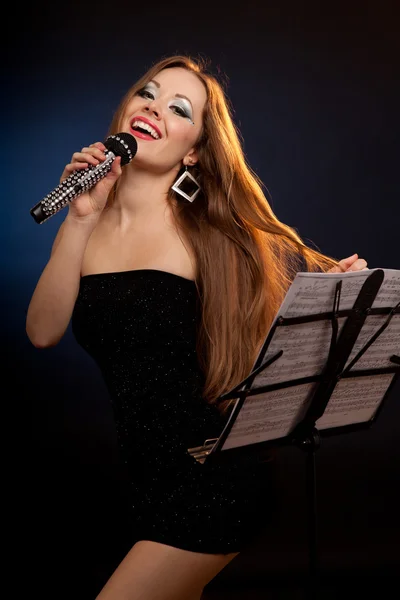 Porträtt av en ung vacker kvinna i svart klänning sång — Stockfoto