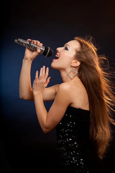 Egy gyönyörű fiatal nő fekete ruhát éneklés portréja — Stock Fotó