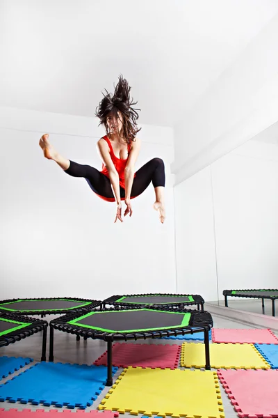 Femme brune sautante sur un trampoline. Porter un haut rouge — Photo