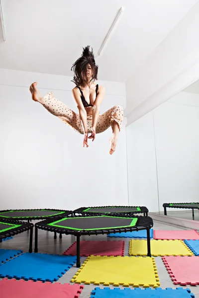 Jumping brunette woman on a trampoline — Stock Photo, Image