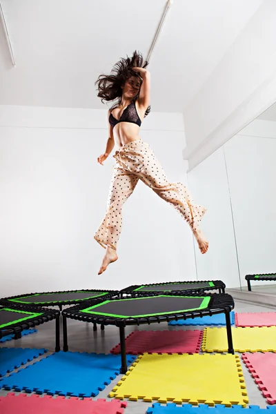 Jumping brunette woman on a trampoline — Stock Photo, Image