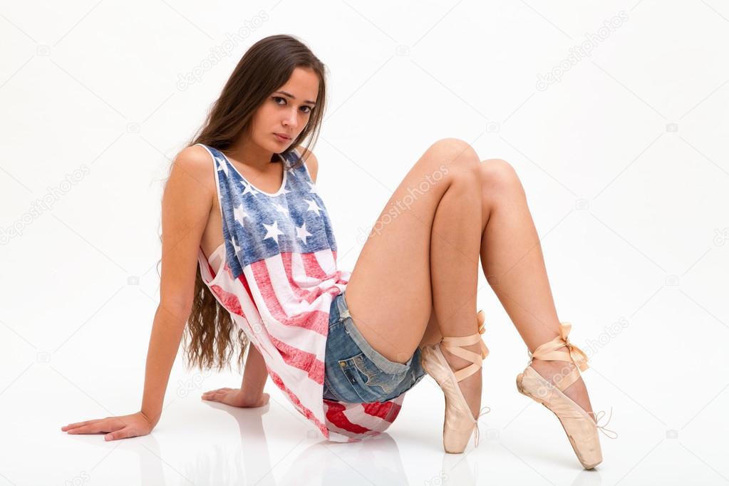 Woman in top colors of USA flag, jeans and ballet tiptoes sitting