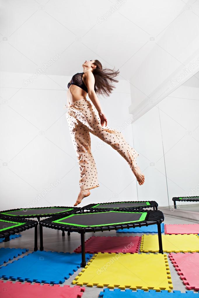 Jumping brunette woman on a trampoline