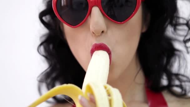 Hot brunette woman with red glasses sexy eating banana — 图库视频影像