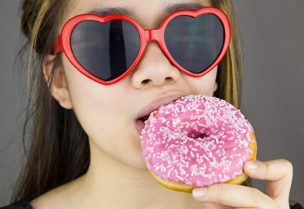 性感的女人，戴着红色的洛丽塔眼镜吃甜甜圈 — 图库照片