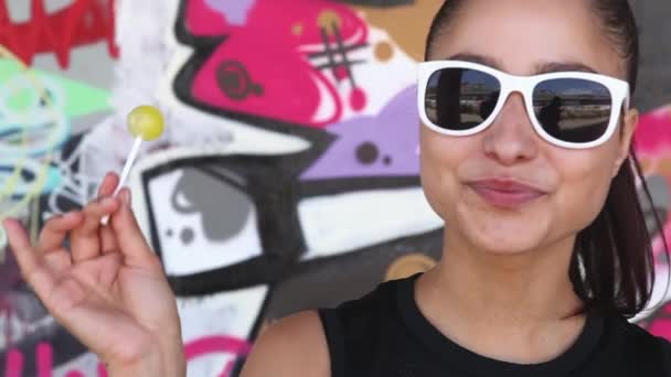 Hermosa mujer comiendo sexy lolly delante de la pared de graffiti — Vídeos de Stock