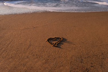 Bir kumsalda kuma kazınmış kalp.