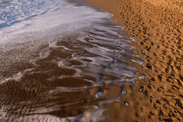 rule-of-thirds composition of a beach with sea fringes and footprints