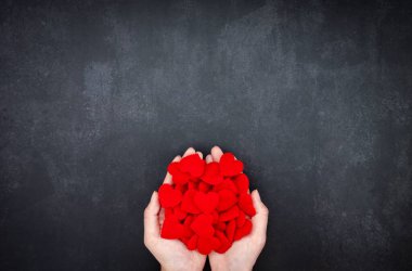 Koyu gri arkaplanda kırmızı kumaş kalplerle dolu eller fotokopi alanı, Sevgililer Günü konsepti