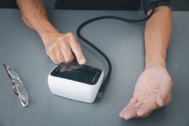 Yaşlı adamın tansiyonu ve kalp atış hızı ölçümü, kan basıncı monitörü, sağlık ve tıbbi konsept.