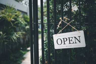 Kafe kapısının önünde yeşil bahçeli bir tabela asılı.