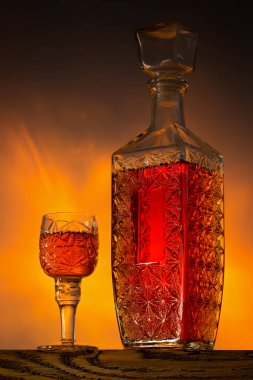 Küçük bir kristal kadehte güçlü bir tentür ve ateşli bir arka planda bir sürahi. Sert içki..