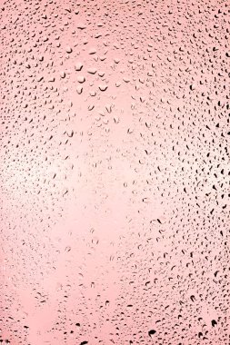 Pembe arka planda, temiz camın yüzeyinden su damlaları akar. Yaratıcılık için doku.