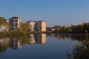 Güneşli bir günde pitoresk bir gölün kıyısındaki modern yerleşim yeri..