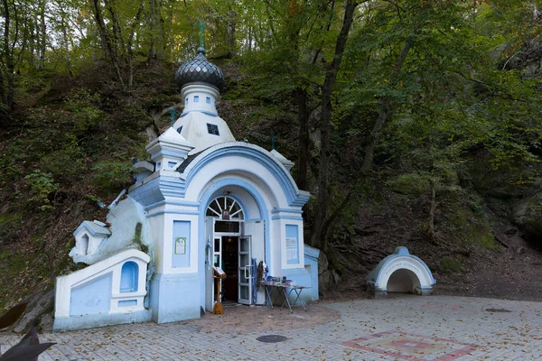 Dağın yamacında bir taşın içine inşa edilmiş eski mavi ve beyaz bir şapel. Acının duaları için bir yer..