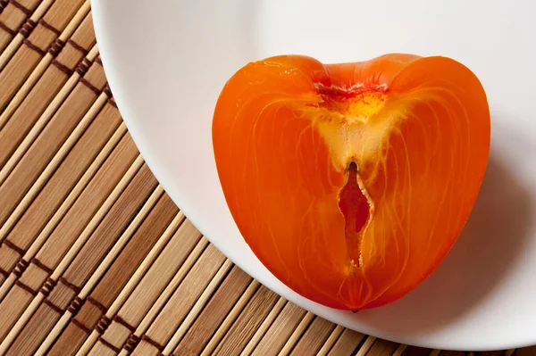 Половина Свіжого Стиглого Апельсинового Хурми Лежить Білій Тарілці Бамбуковому Килимку — стокове фото