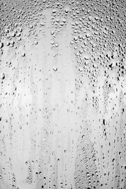 Su damlaları temiz camın yüzeyinden gri arka planda akar. Yaratıcılık için doku.