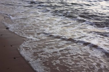 Akşam kumsalında deniz suyunun köpüklü kenarı..