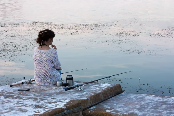 A girl fishing with a fishing rod in the evening on the river.