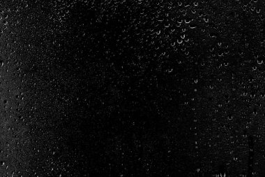 Temiz camın yüzeyinden aşağı siyah bir zemin üzerinde su damlaları akar. Yaratıcılık için doku.