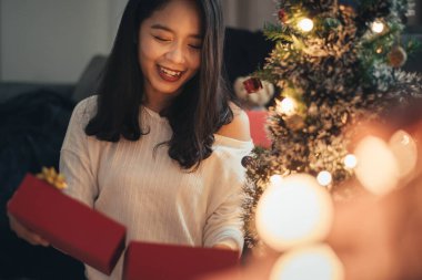 Bir kadın Noel günü sürpriz yapıp hediye kutusuna bakıyor. Noel hediyeli mutlu kız evde Noel 'i kutluyor..