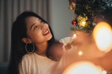 Kadın evdeki Noel ağacını süslüyor. Gülümseyen genç kadın Noel 'i kutluyor, Mutlu Noeller ve yeni yıl arifesi konsepti.