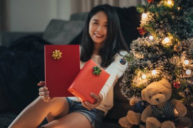 Noel 'i evde kutlamak için hediye kutusu gösteren bir kadın. Mutlu Noeller ve yeni yıl arifesi. Noel hediye kutusuna odaklan..