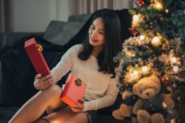 Bir kadın Noel günü sürpriz yapıp hediye kutusuna bakıyor. Noel hediyeli mutlu kız evde Noel 'i kutluyor..